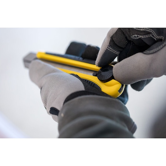 Photo of STANLEY 0-10-425 utility knife held in gloved hands, close-up showing adjustment knob.