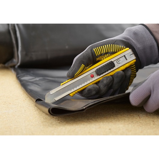 STANLEY 0-10-431 utility knife cutting black material, close-up of gloved hand using the tool.