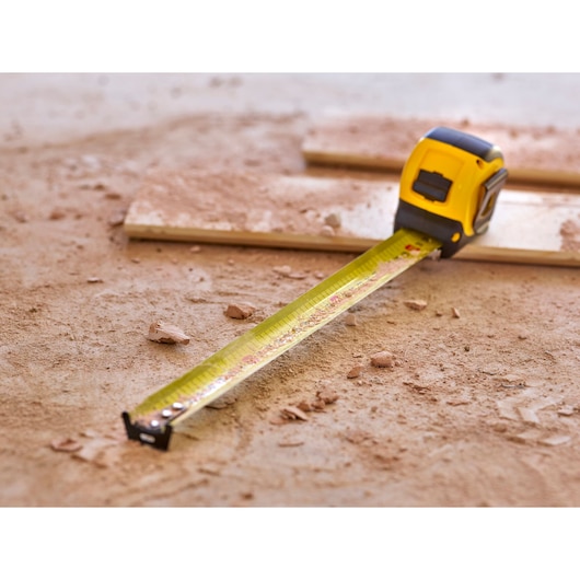 STANLEY 0-33-720 tape measure extended on dusty construction floor, photography product.
