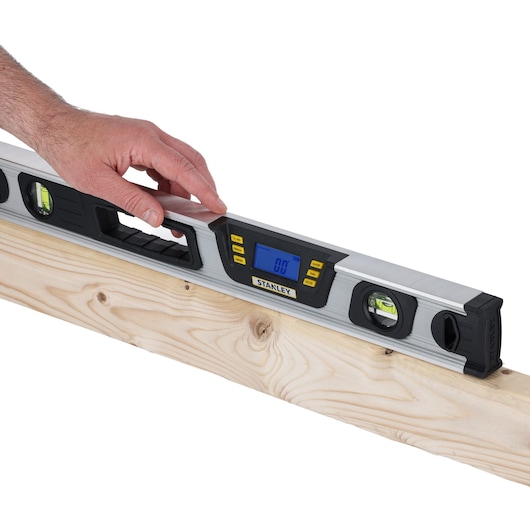 Photo of STANLEY 0-42-065 digital spirit level on wood, LCD display, hand adjusting tool.