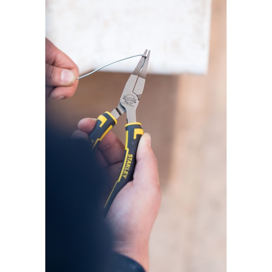STANLEY 0-84-495 pliers with yellow and black handles in use bending wire, close-up photography.