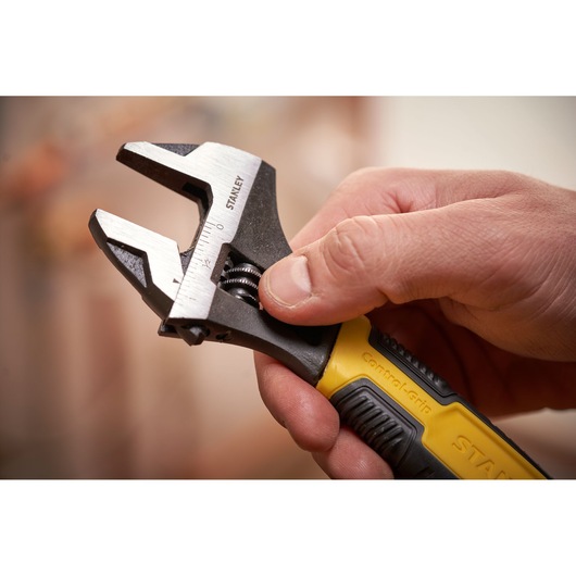 STANLEY 0-90-949 adjustable wrench with yellow and black grip held in hand, close-up photography.