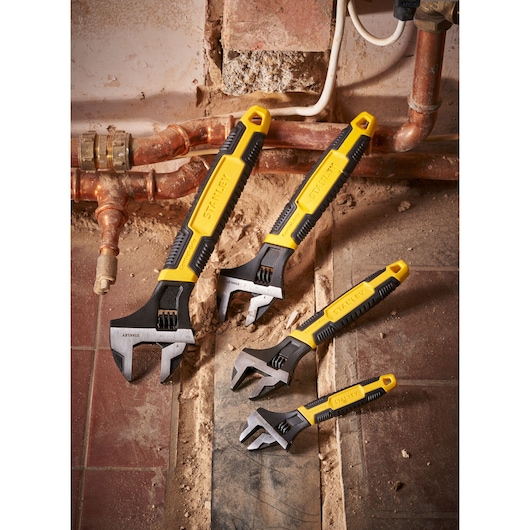 STANLEY 0-90-950 adjustable wrench set with yellow handles shown on a construction site floor.