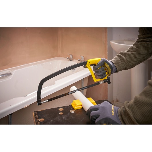 STANLEY 1-15-122 hacksaw cutting white PVC pipe in bathroom, close-up action shot.
