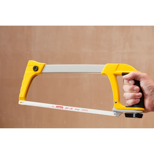 STANLEY 1-20-110 hacksaw with yellow handle, side view, held in hand, showing bi-metal blade.