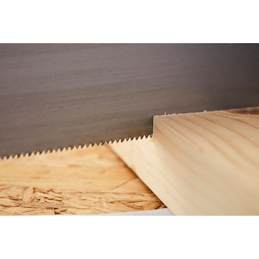 STANLEY 1-20-600 hand saw blade cutting wood plank, close-up side angle.