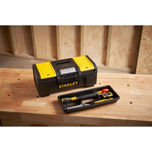 STANLEY 1-79-216 black and yellow toolbox on wooden workbench, open tray showing hand tools, workshop background.
