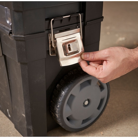 STANLEY 1-93-968 tool box close-up showing metal latch and wheel, hand unlocking front latch.