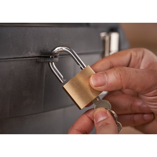 STANLEY 1-93-968 brass padlock unlocking with key on black surface, close-up photography.