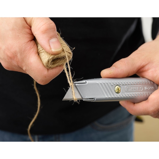 Photo of STANLEY 2-10-199 utility knife cutting twine, close-up of hands and tool in use.