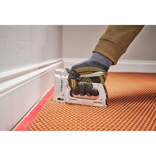 Photo of STANLEY 6-TR110 manual staple gun used to fasten carpet, close-up, side angle.