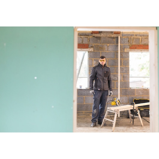 STANLEY FME301 photography of a worker in a jacket standing in a construction area with tools and saw bench.