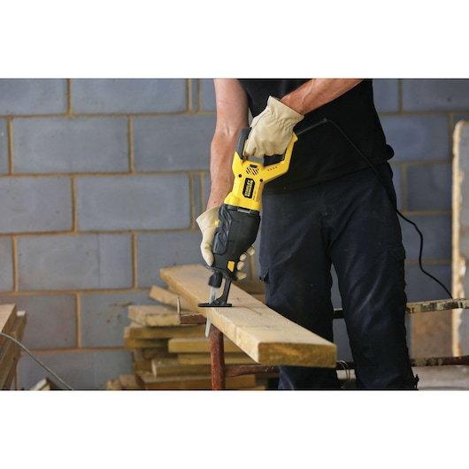 STANLEY FME365K reciprocating saw in use cutting wood plank, construction setting, product demonstration.
