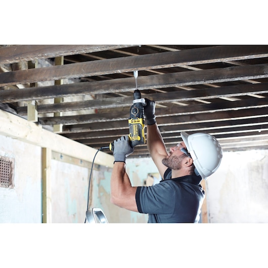 STANLEY FMEH1100K hammer drill used by worker for overhead drilling in construction site.