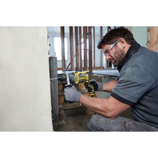 Photo of worker using STANLEY FMEH750K corded hammer drill to drill into concrete wall at construction site.