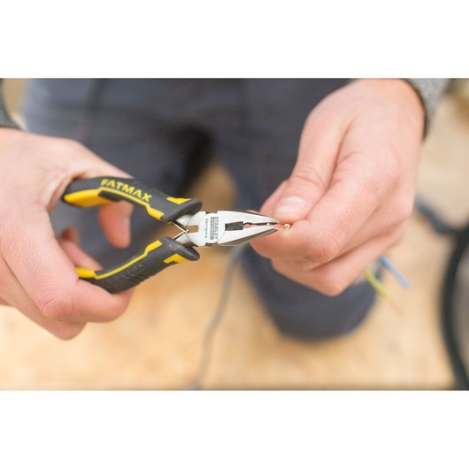 STANLEY FMHT0-80516 pliers held by hand, gripping a wire, black and yellow handle, close-up photo.