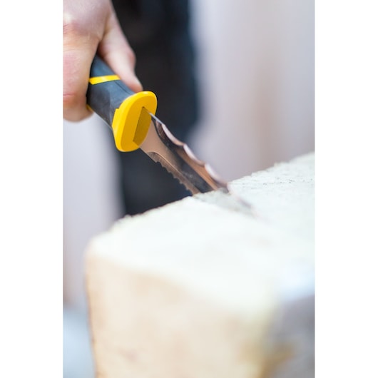 STANLEY FMHT10327-1 drywall saw with yellow-black handle cutting gypsum board, close-up side angle.