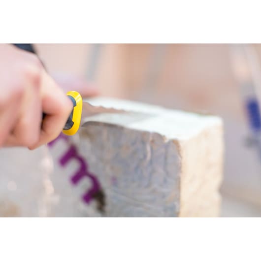 STANLEY FMHT10327-1 utility knife with yellow and black handle cutting insulation material, close-up.