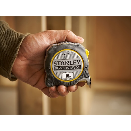 Photo of STANLEY FMHT38217-0 FATMAX tape measure, 8m length, held in hand, black and yellow casing.