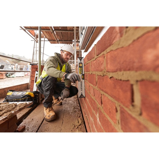 STANLEY FMHT43670-1 spirit level used by construction worker checking vertical alignment of brick wall on site.