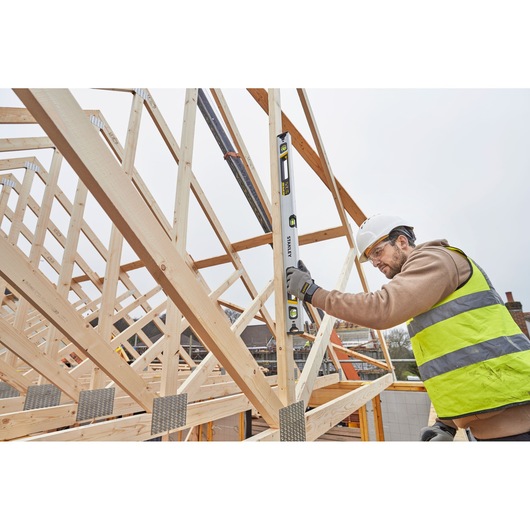 STANLEY FMHT43674-1 spirit level used by worker on timber roof frame at construction site.