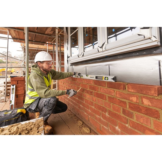 Photo of STANLEY FMHT43674-1 spirit level used by a construction worker on a brick wall at a building site.