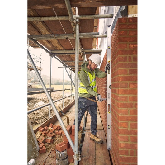 STANLEY FMHT43679-1 spirit level in use by a construction worker checking a brick wall on scaffolding.