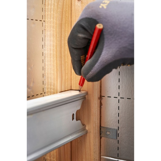Stanley FMHT43679-1 photography of gloved hand marking wood near metal rail in construction setting.