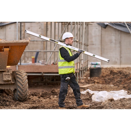 STANLEY FMHT43679-1 spirit level carried by worker in high-visibility vest at construction site.