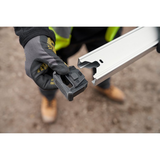 Photo of STANLEY FMHT43679-1 photography showing hand holding black tool attachment and silver rail outdoors