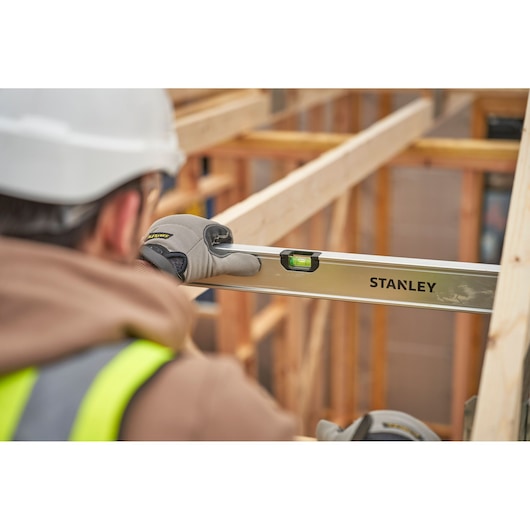 Photo of STANLEY FMHT43680-1 spirit level used by worker at construction site, clear side angle view.