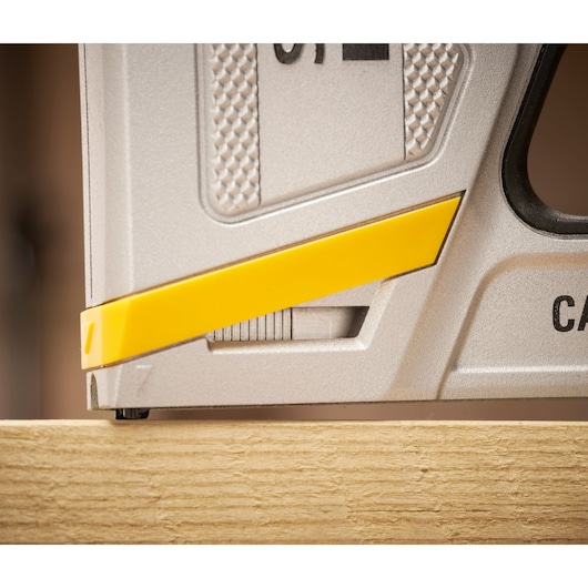 STANLEY FMHT70100-0 photography of staple gun corner, silver and yellow detail on wood surface.