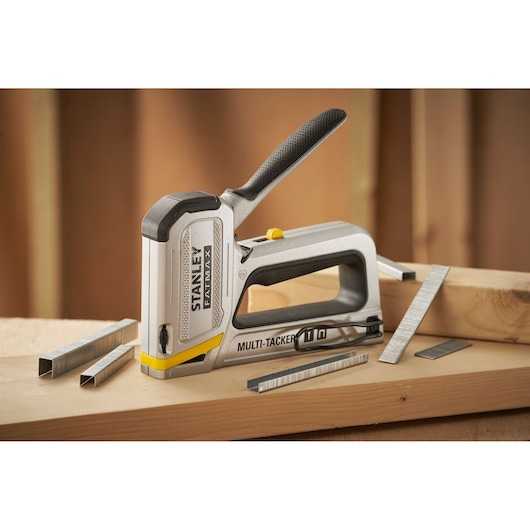 Stanley FMHT70250-0 stapler tool with staples on a wooden surface, FATMAX Multi-Tacker ergonomic handle.