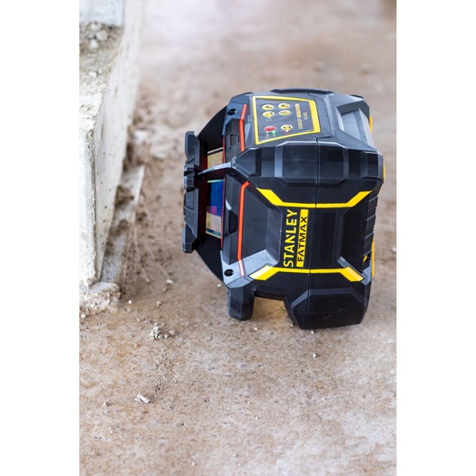 STANLEY FMHT77449-1 laser level device on concrete floor, angled view, black and yellow housing.