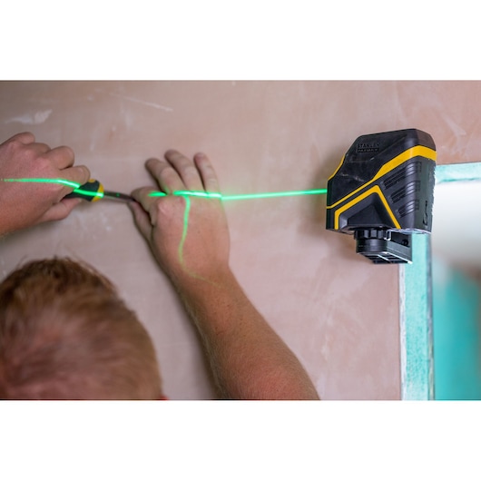 STANLEY FMHT77595-1 laser level projecting green line onto wall, used for alignment during installation.