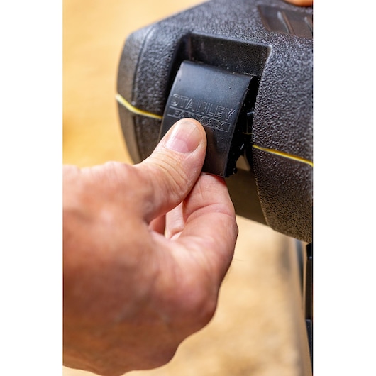 Photo of a hand opening the latch on a STANLEY toolbox, SKU FMMT82685-1, close-up view.