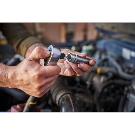 STANLEY FMMT82826-1 ratchet and socket in use during automotive repair, close-up view, silver tools.