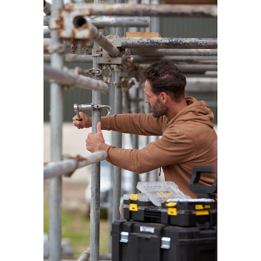 STANLEY FMMT82827-1 ratchet socket and wrench set in use on scaffolding, toolboxes visible, outdoor setting.