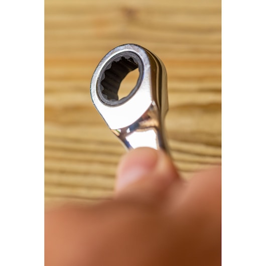 Close-up of STANLEY FMMT82848-0 ratcheting wrench held by hand, showing gear end, indoor setting.