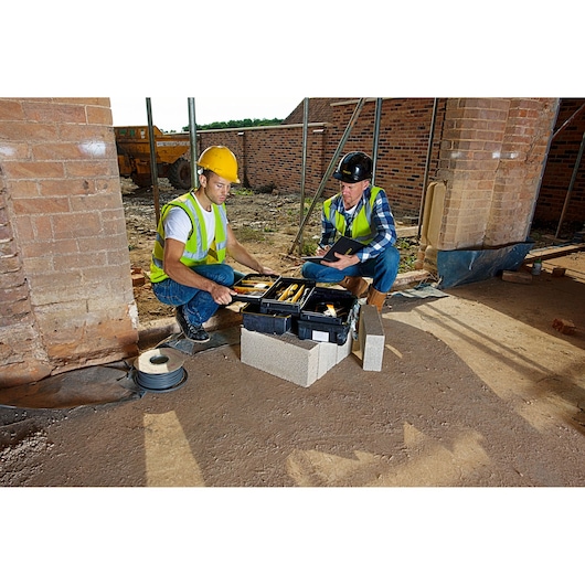 STANLEY FMST1-71219 tool box open on site, showing hand tools, used by two construction workers.