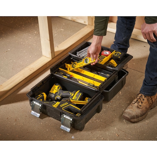 STANLEY FMST1-71219 black toolbox with multiple compartments and yellow hand tools, indoor workspace.