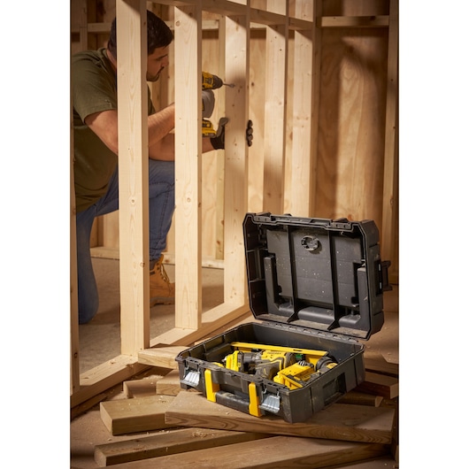 STANLEY FMST1-71967 tool case with yellow latches open on construction site with tools inside.