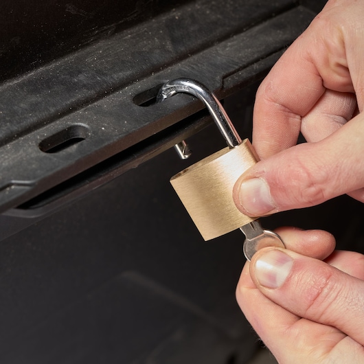Photo of STANLEY FMST1-73601 brass padlock being unlocked with a key on a black metal latch.