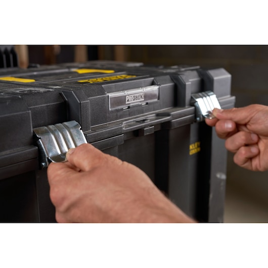 Photo of hands opening metal latches on STANLEY FMST1-75753 tool box, close-up view of front locking system.