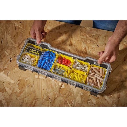 STANLEY FMST1-75781 organiser box with assorted plastic and metal fasteners, top view, hands holding.