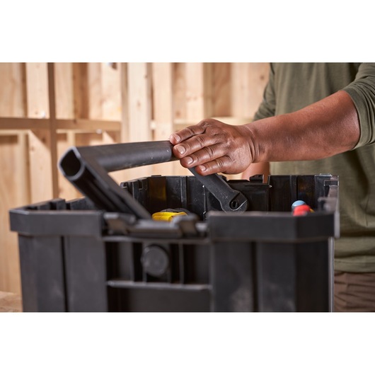 Photo of STANLEY FMST1-75794 black plastic tool box being carried by handle, tools visible inside.