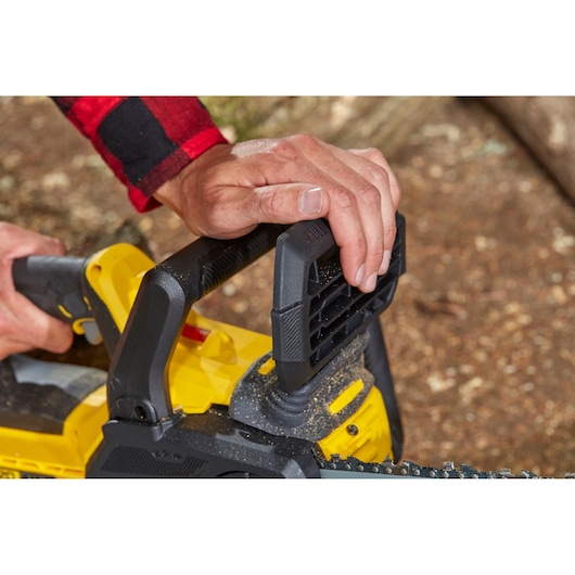 STANLEY SFMCCS630B chainsaw close-up, hands gripping black handle, yellow body visible.