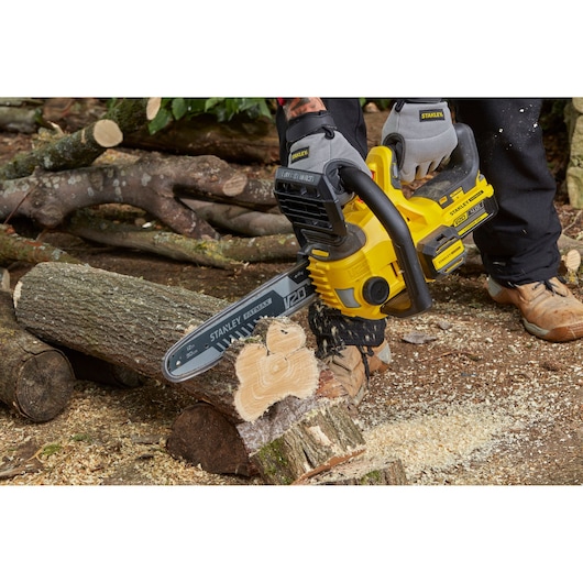 Stanley SFMCCS630B chainsaw cutting log outdoors, yellow and black design, close-up action shot.