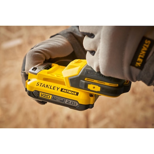 Photo of STANLEY SFMCD714D2T FATMAX V20 2.0Ah lithium-ion battery with gloved hands holding power tool.