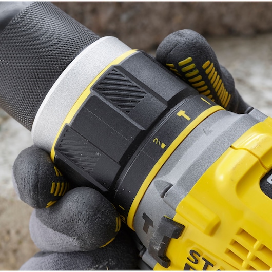 STANLEY SFMCD721B drill close-up showing grip and adjustable torque settings, with gloved hand holding tool.